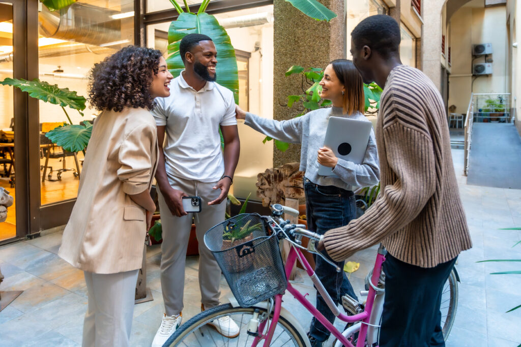 Cheerful and diverse colleagues talking at the entrance of a modern and sustainable coworking space